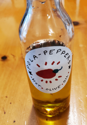 Hot chili pepper flakes and olive oil in a bottle labelled pola peppers